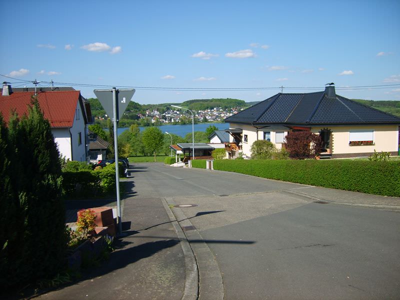 Wohnstraße mit Blick auf den Wiesensee und bewaldete Hügel im Hintergrund