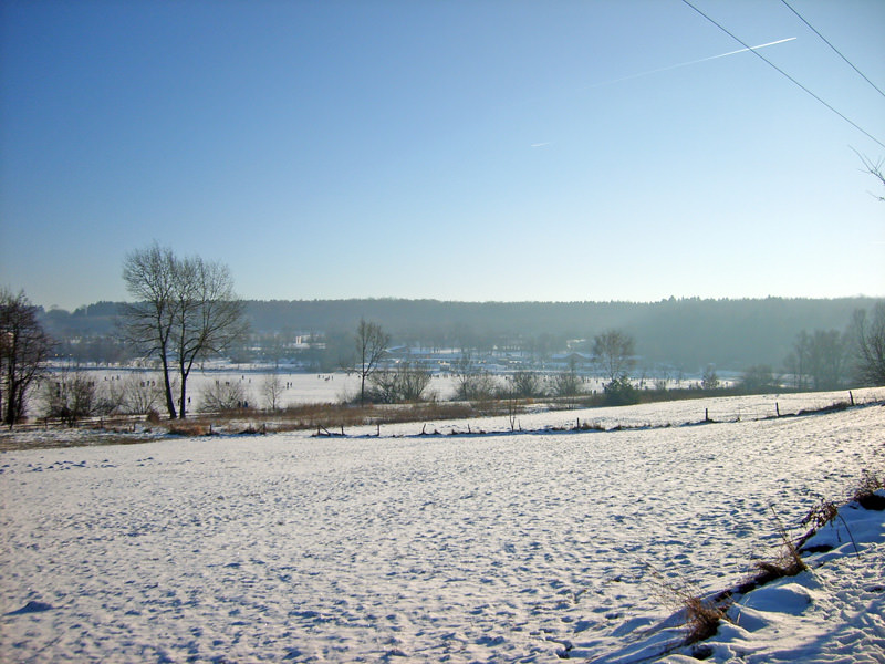 Verschneite Felder bei Stahlhofen am Wiesensee mit Blick auf Ortschaft und bewaldete Hügel im Hintergrund